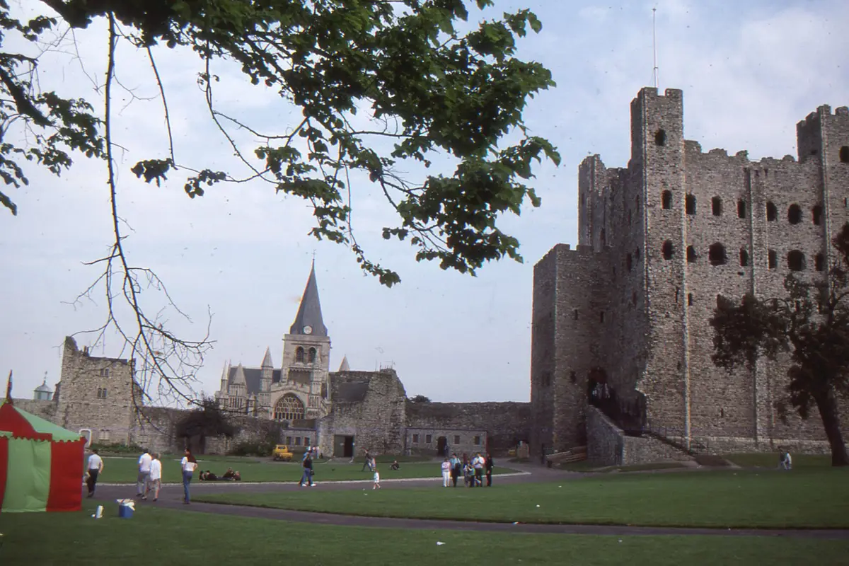 Rochester Castle keep with the cathedral tower behind it, seen across the castle gardens.