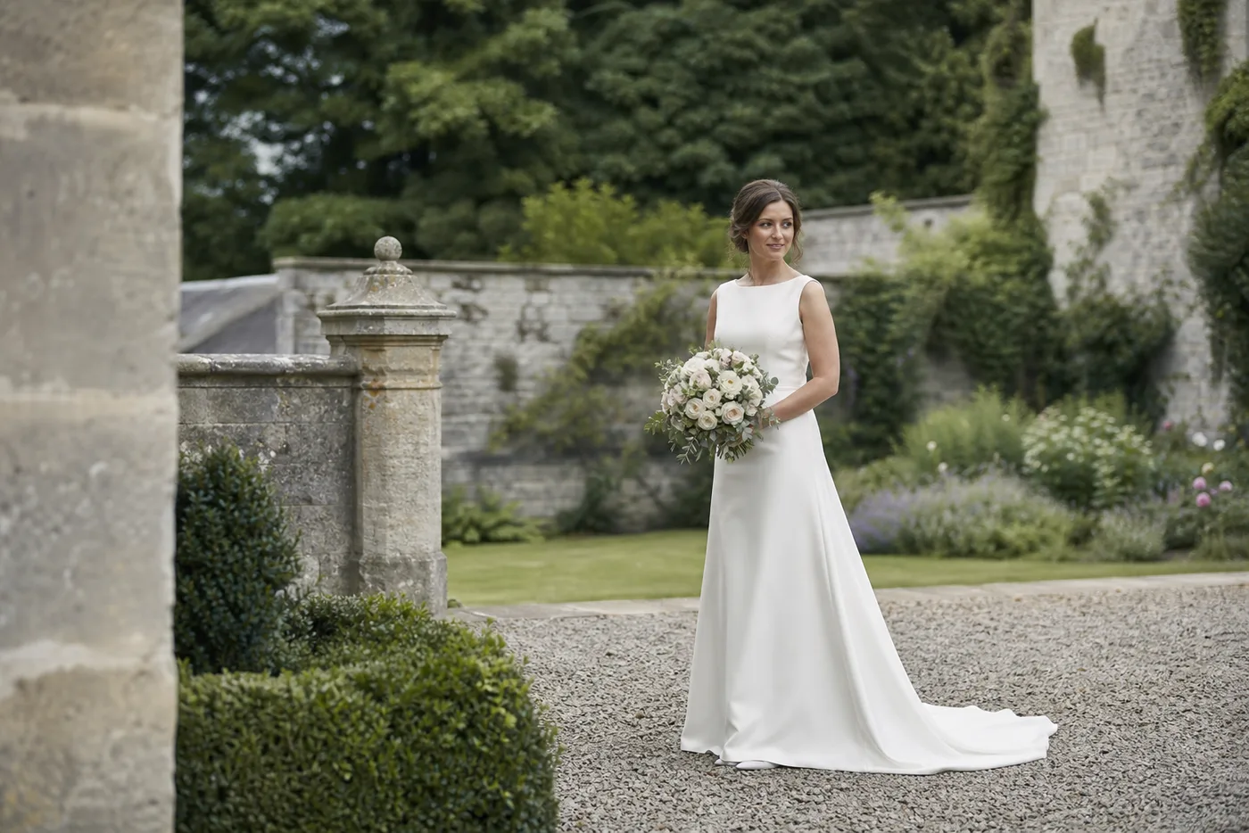 Bride in an ivory wedding dress standing in a garden